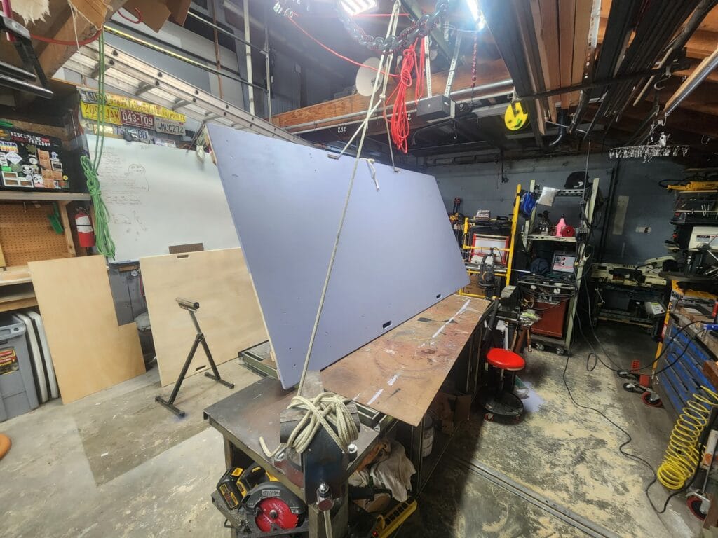 climbing wall in workshop held up by ropes for painting.