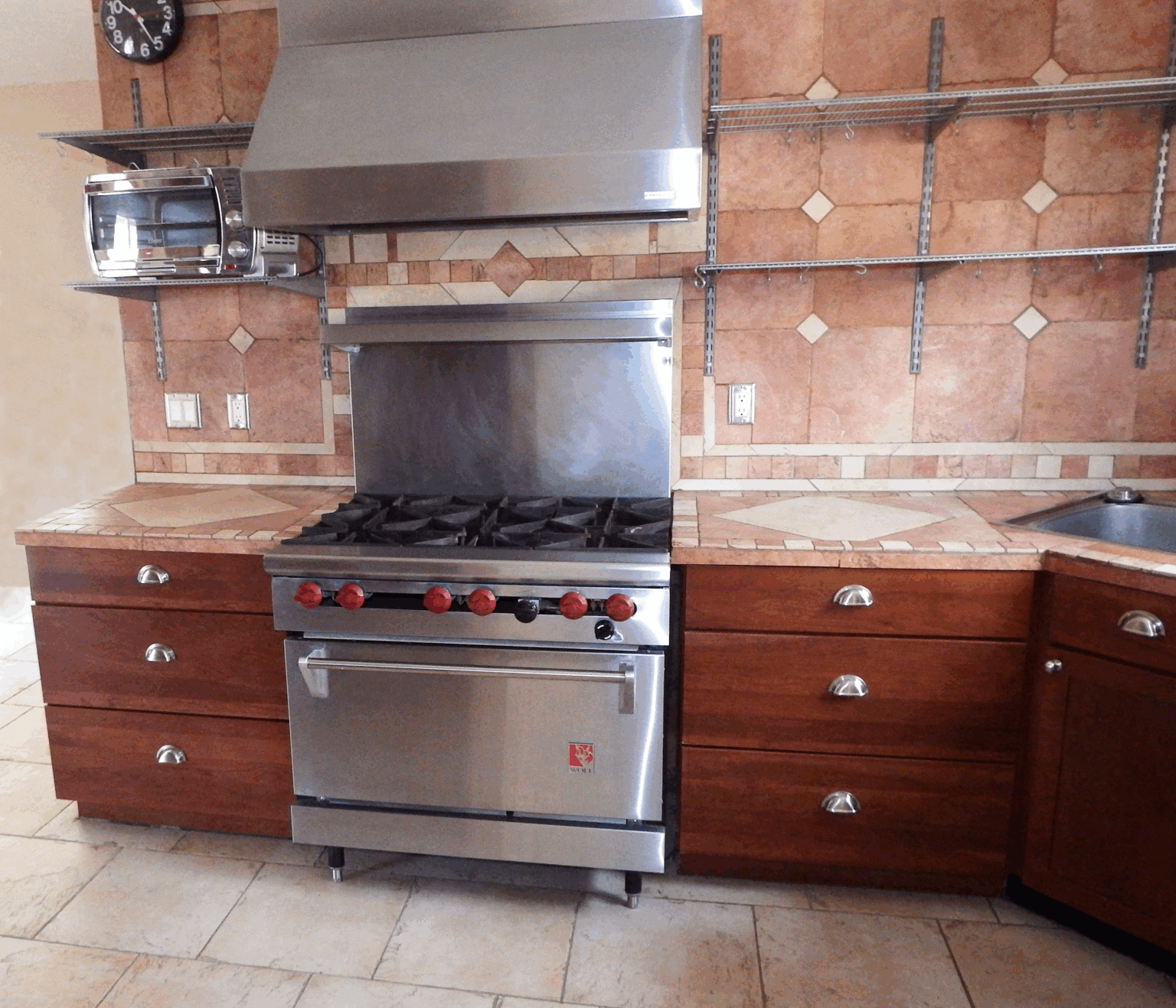 rustic tiled kitchen, large exhaust hood and built in, flush mounted shelves with storage to hang pots, pans and harge utensils